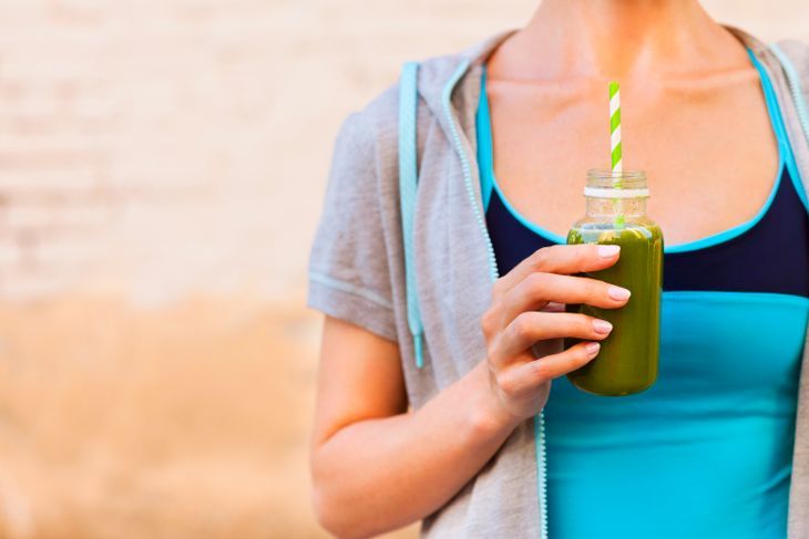 Frau trinkt Gemüse-Smoothie nach Fitness-Lauftraining am Sommertag. Fitness- und gesundes Lifestyle-Konzept
