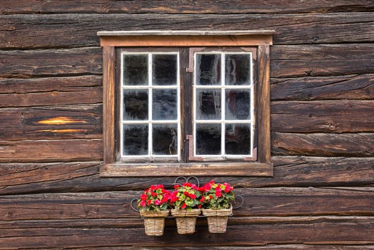 Blick auf ein sehr schönes Fenster eines Holzhauses mit Begonien vor dem Fenster