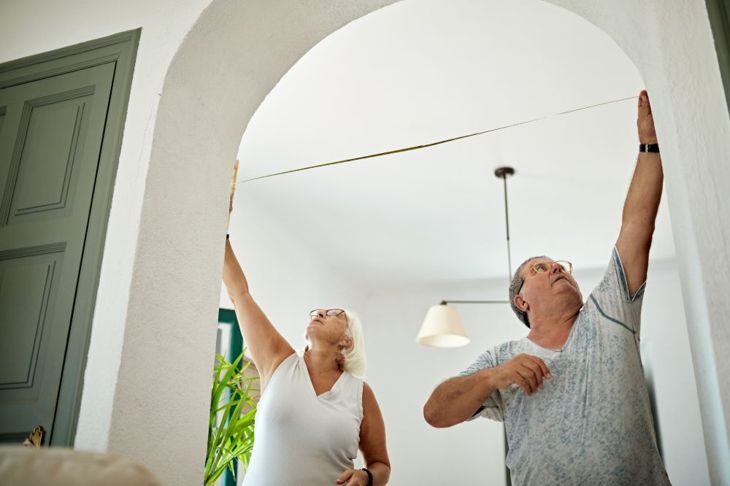 älterer Mann und Frau, die die Tür zum Wohnzimmer messen