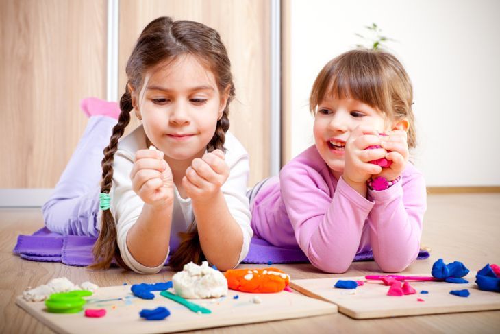 Zwei kleine Mädchen spielen mit Plastilin.