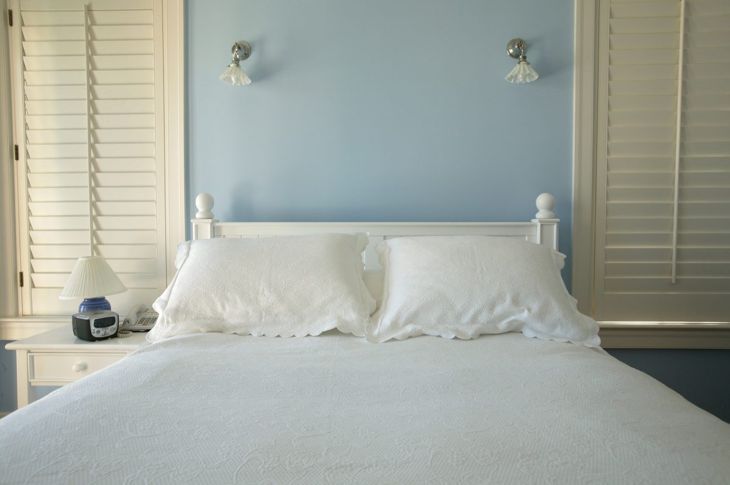 Schlafzimmer mit blauen Wänden und weißem Bett.