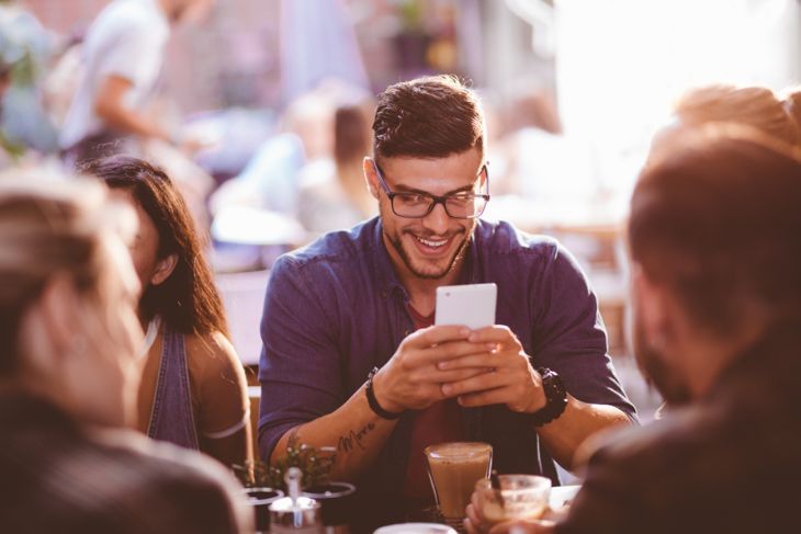 Glücklicher Hipster-Mann im Café SMS auf dem Handy