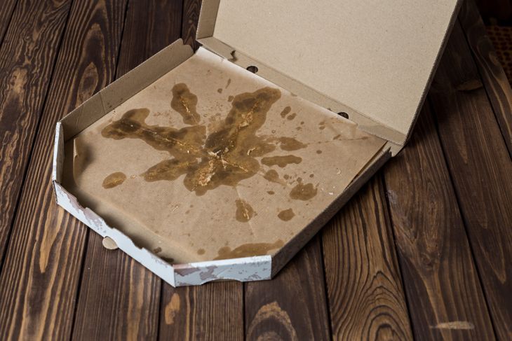 fettiger gebrauchter Pizzakarton auf Holzboden