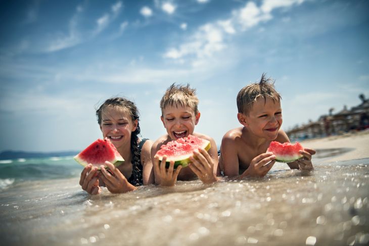 Glückliche Kinder essen Wassermelone am Strand