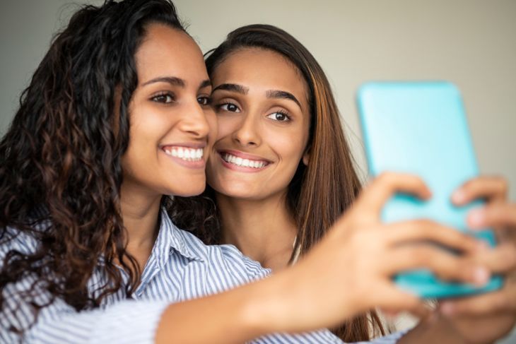 Zwei junge Brasilianerinnen fotografieren sich auf dem Smartphone, posieren, lächeln, fröhlich, soziale Medien