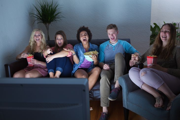 Teenager-Gruppe von Freunden, die zusammen einen humorvollen Film oder eine Fernsehsendung ansehen