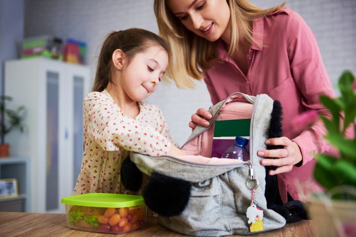 Mama und kleines Mädchen organisieren Schulrucksack