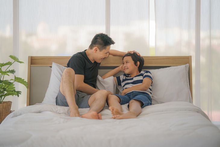 Vater und kleiner Sohn sprechen vor dem Schlafengehen im Bett