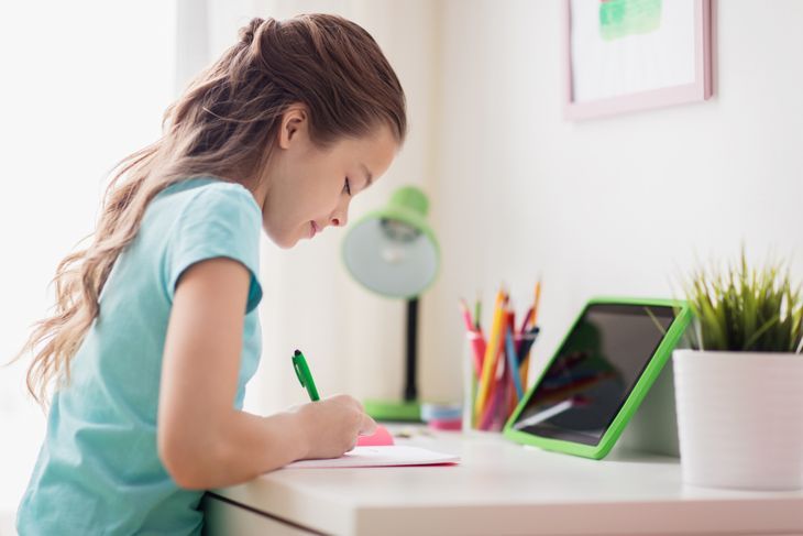 junges Mädchen macht Hausaufgaben an ihrem Schreibtisch zu Hause