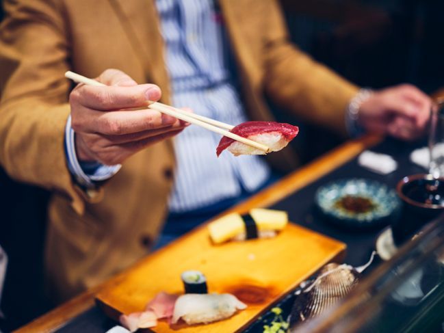 Ein japanischer Sushi-Koch, der Kunden in einem kleinen Sushi-Shop in Tokio, Japan, bedient.