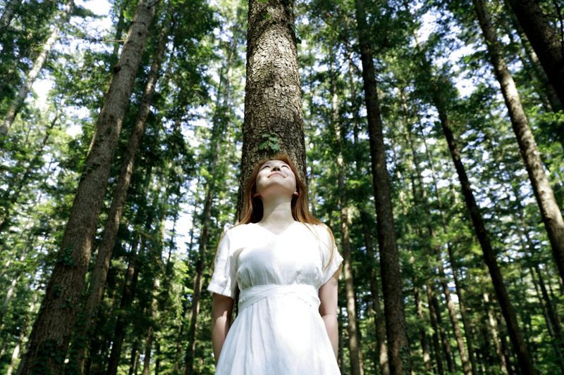 Frau stützte sich auf Baum im Wald