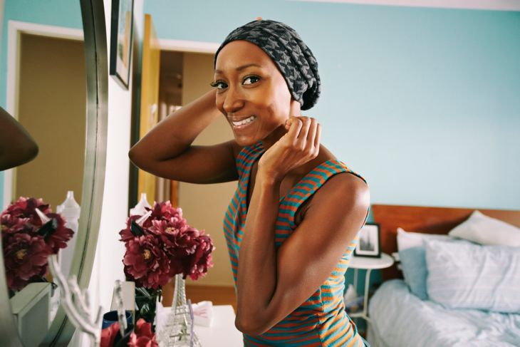 Lächelnde afroamerikanische Frau, die im Schlafzimmer steht