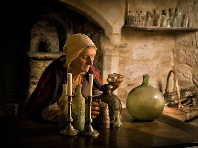 mittelalterliche Frau oder Hexe, die an ihrem Tisch arbeitet