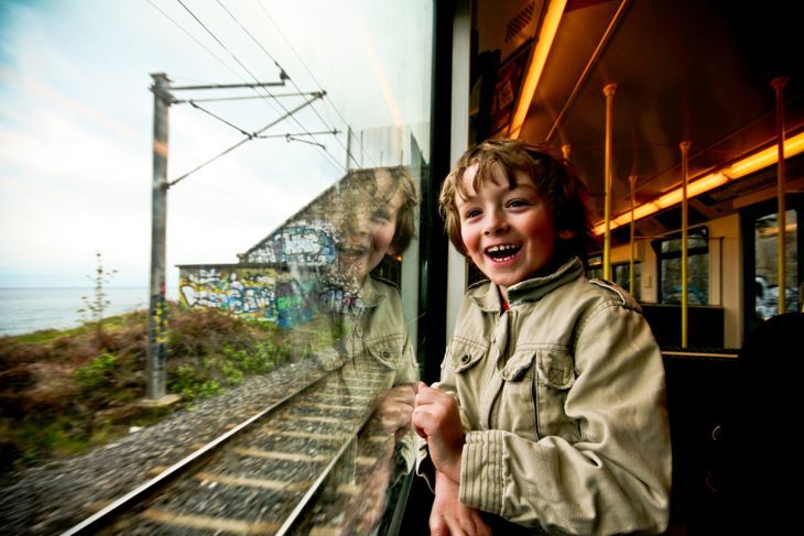 Ein sehr aufgeregter Junge schaut aus einem Zugfenster.