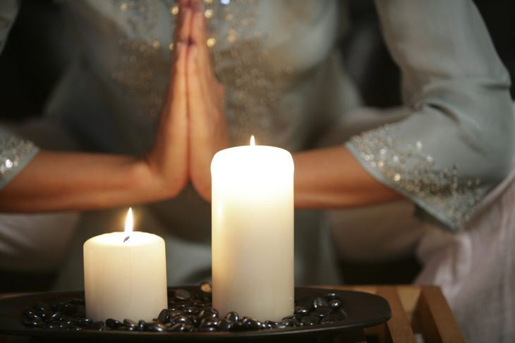 Spirituelle Frau, die Yoga mit Kerzen praktiziert