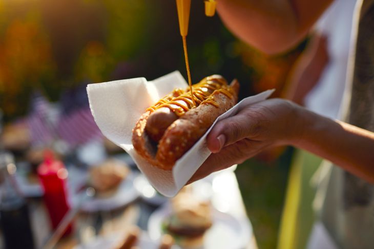 Familie mit mehreren Generationen beim Picknick im Hinterhof, Hot Dog essen und den 4. Juli feiern - Unabhängigkeitstag. Konzentrieren Sie sich auf Hot Dog mit Senf