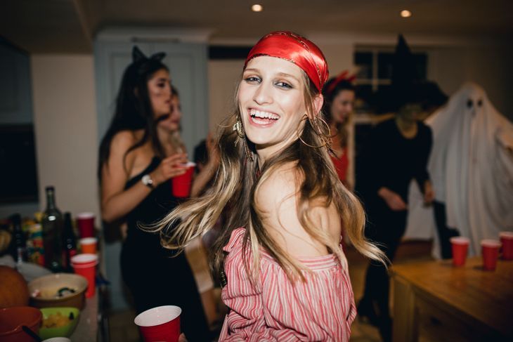 Frau, die auf einer Halloween-Party als Pirat verkleidet ist und lacht und tanzt, während sie zurück zur Kamera blickt.